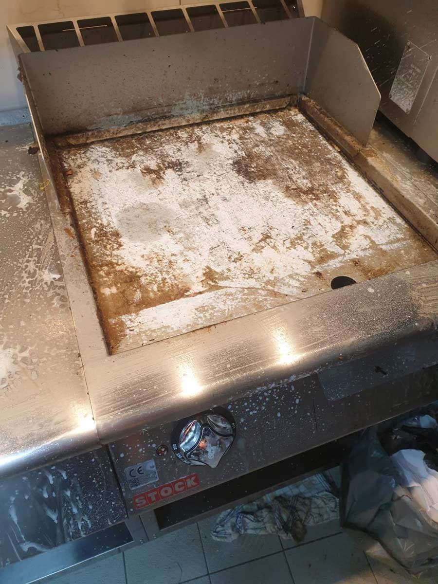 Grillplatte aus Edelstahl in einer Gastroküche, stark verkrustet, vor der Reinigung